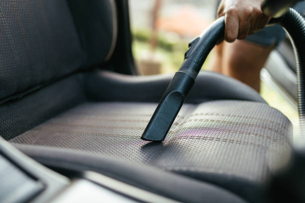 istock Man Vacuuming Car Seat Interior with Vacuum Cleaner in Sunlight 2206281174