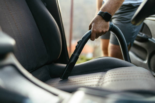 istock Man Vacuuming Car Seat Interior with Vacuum Cleaner in Sunlight 2206281184