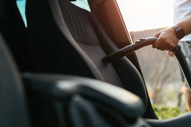 istock Man Vacuuming Car Seat Interior with Vacuum Cleaner in Sunlight 2206281224