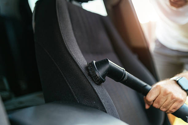 istock Man Vacuuming Car Seat Interior with Vacuum Cleaner in Sunlight 2206281253