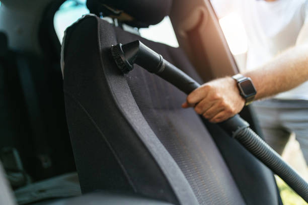 istock Man Vacuuming Car Seat Interior with Vacuum Cleaner in Sunlight 2206281273