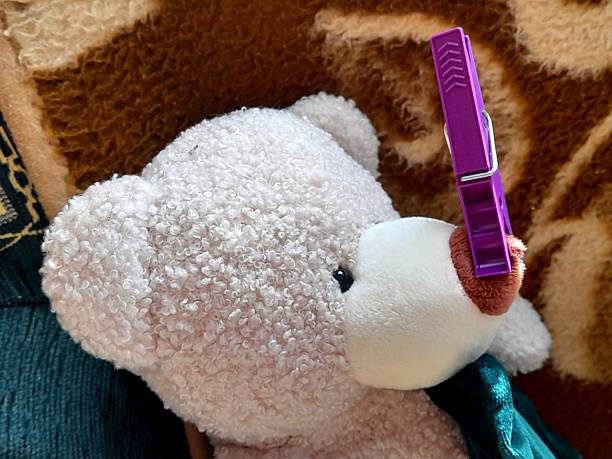 This image features an old, yet cute teddy bear wearing a gray scarf, lying on a white background. The bear shows signs of wear, emphasizing its history and beloved character. Concept for themes such as childhood memories, comfort, security, and nostalgia. Ideal for advertisements, articles about toys, nursery decoration, and blogs about childhood and memories