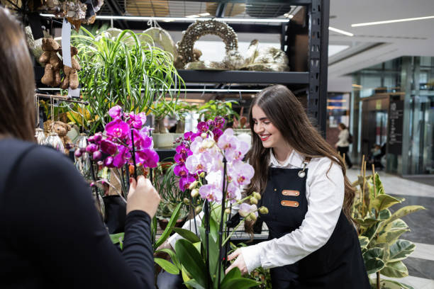 istock Florist arranging orchids in flower shop with customer choosing 2206284514