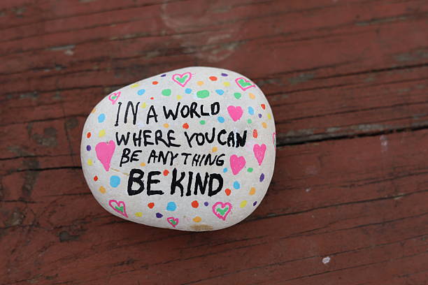 istock Be anything be kind kindness rock on weathered wooden picnic table surface 2206285688
