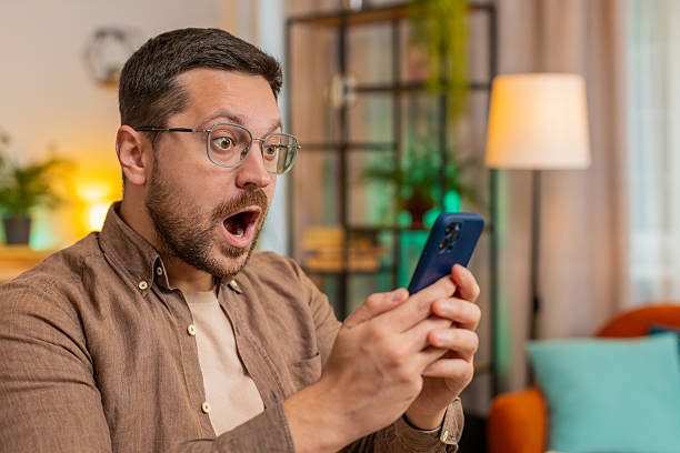 istock Caucasian young man guy using smartphone shocked by sudden victory sitting in home office room 2206294507
