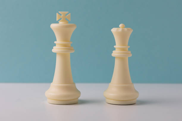 istock White king and queen chess pieces standing on white surface with teal background 2206295700