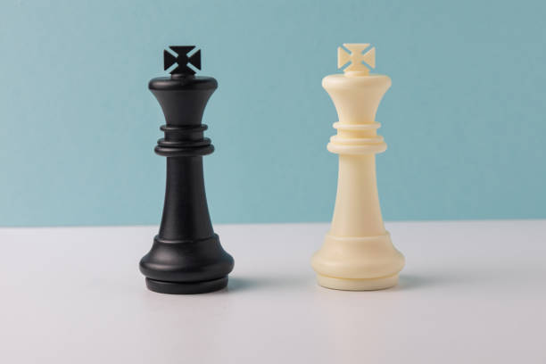 istock Black and white king chess pieces facing each other on white and blue background 2206295826