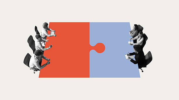 istock Corporate alignment. Business teams positioned around puzzle table, symbolizing strategic alignment, negotiations, structured collaboration 2206303043