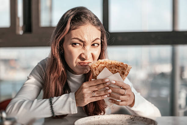 istock Young woman sitting at a table, eating a piadina while making a disgusted face, expressing her dissatisfaction with the meal 2206304473