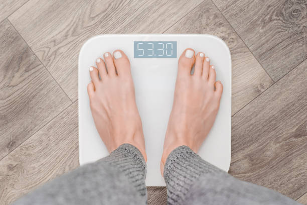 istock woman checking her weight on digital scale 2206334583