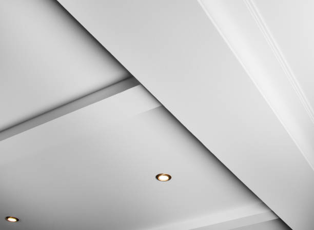 istock Suspended and grid ceiling with LED spots lamps and drywall construction in empty room in house interior. Stretch ceiling white and complex shape. 2206337979