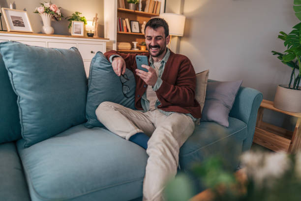 istock Man relaxing on sofa, enjoying social media on smartphone 2206338923