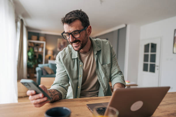 istock Freelancer smiling and using smartphone and laptop at home 2206338983