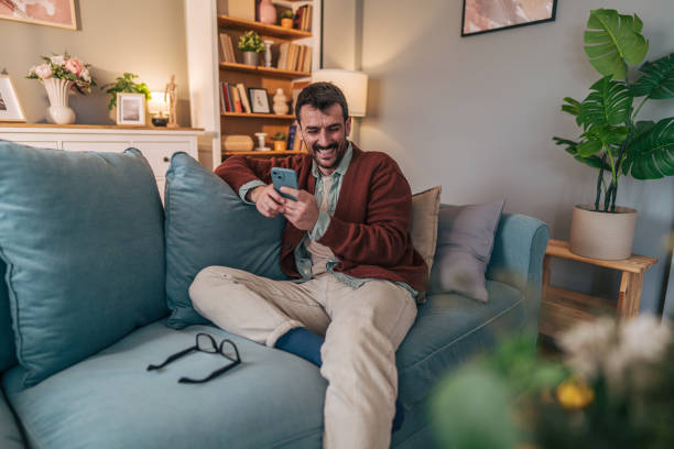 istock Happy man relaxing on sofa using smartphone at home 2206339036