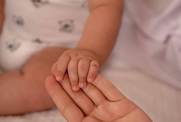 istock Baby's hand holding mother's finger, close-up 2206339328