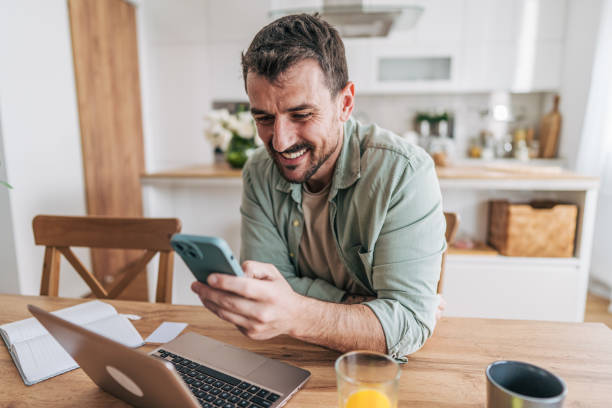 istock Freelancer smiling and reading a text message on smartphone at home 2206339967