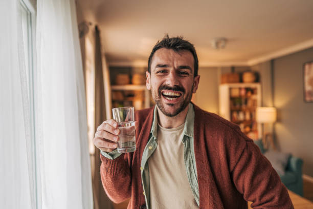 istock Happy man drinking water and smiling at home 2206340306