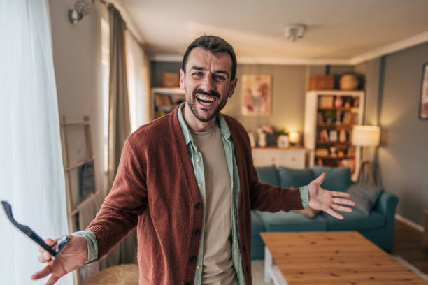 istock Cheerful man holding eyeglasses and smiling at home 2206340393