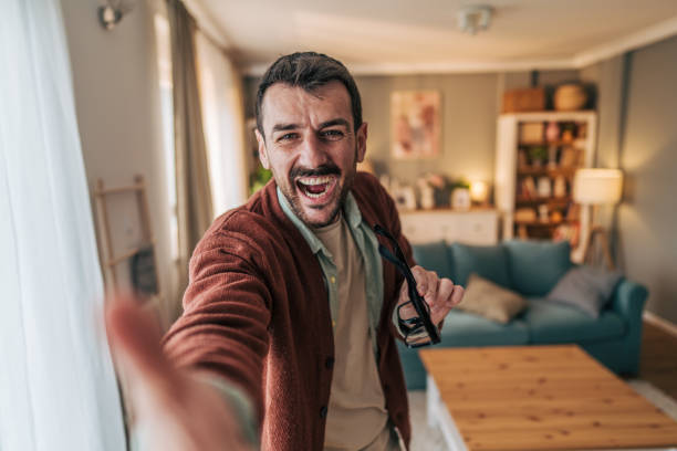 istock Enthusiastic man taking selfie at home, reaching out to camera with excitement 2206340643