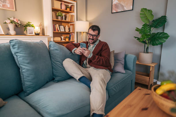 istock Relaxed man using smartphone on sofa in living room 2206340653