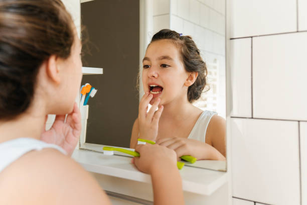 istock Young Girl Smiling in the Mirror While Brushing Her Teeth 2206345378