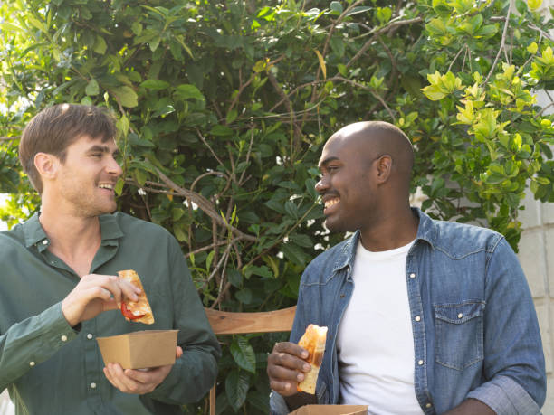 istock Two young men enjoying the moment while eating at a park after event 2206348165