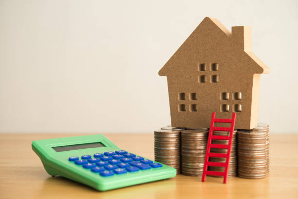 istock House model, red ladder, stack coins and calculator on wooden table white wall background. 2206350904
