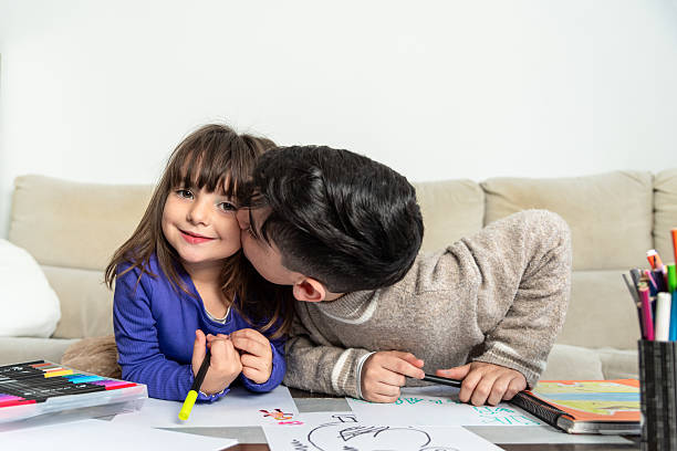 istock Brother kissing sister while drawing on table at home 2206351577