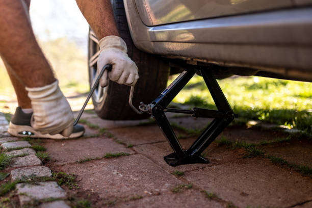istock Changing a Tire Using a Car Jack on a Brick Driveway 2206351588