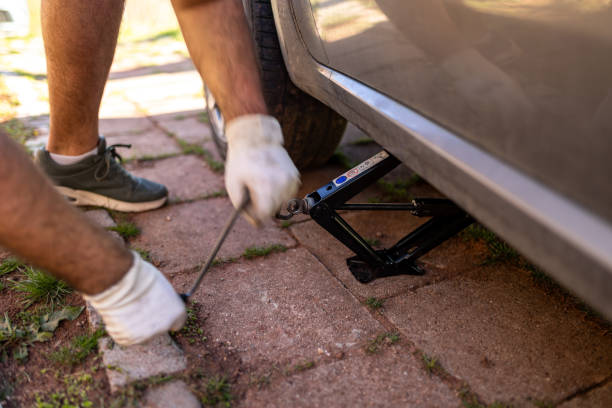 istock Changing a Tire Using a Car Jack on a Brick Driveway 2206351610