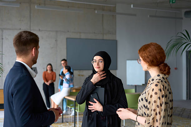 istock A diverse group of business professionals engages in a conversation during a work break in the office, with their colleagues visible in the background, fostering collaboration and connection 2206351868
