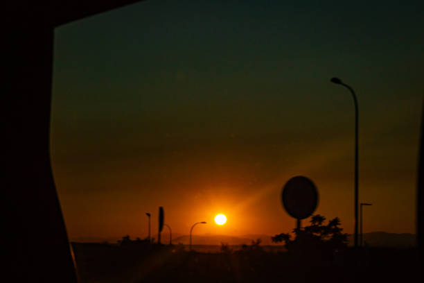 Orange sunset on the road during the trip. The sun sets on the horizon and the silhouettes of the road signs can be distinguished