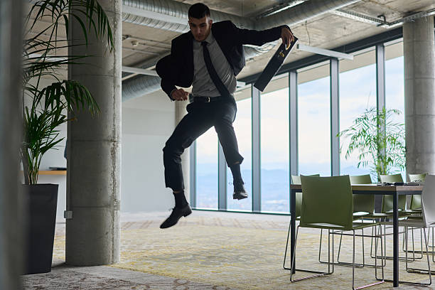 istock A businessman ecstatically jumping in a modern office, holding a briefcase in his hands, celebrating a moment of success and triumph. 2206362613