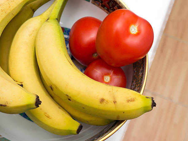 Bananas and tomatoes on a plate.