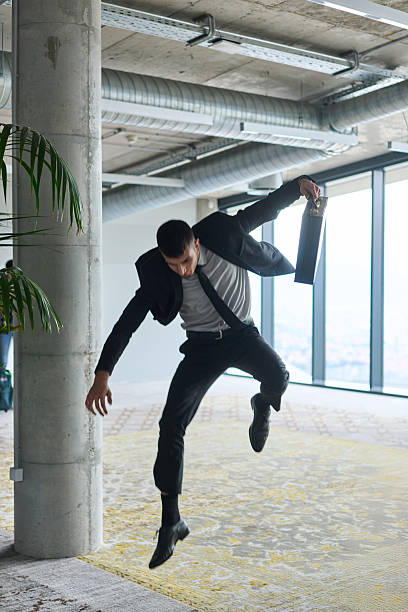 istock A businessman ecstatically jumping in a modern office, holding a briefcase in his hands, celebrating a moment of success and triumph. 2206364096