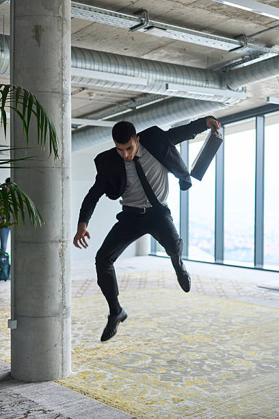 istock A businessman ecstatically jumping in a modern office, holding a briefcase in his hands, celebrating a moment of success and triumph. 2206365601