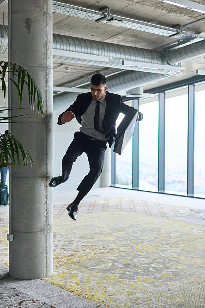 istock A businessman ecstatically jumping in a modern office, holding a briefcase in his hands, celebrating a moment of success and triumph. 2206367229