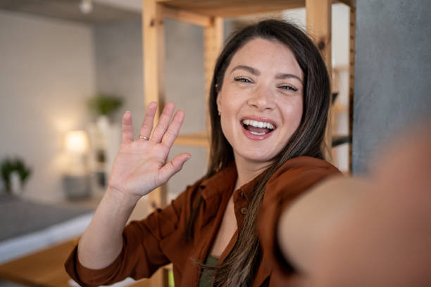 istock Young woman waving hand while taking selfie at home 2206367337