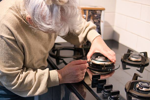 istock An elderly lady is installing a burner on a gas stove. 2206368537