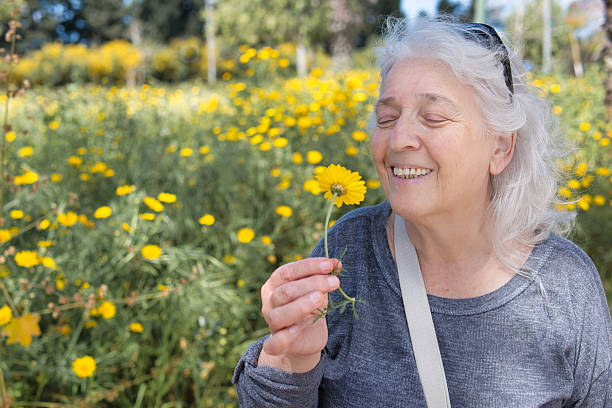 istock Smiling elderly lady admiring a small wildflower. 2206368538