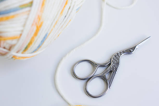 Intricate sewing scissors and colorful yarn on white surface.