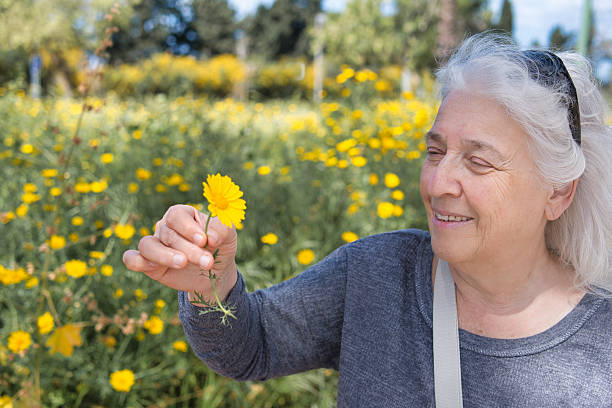 istock Smiling elderly lady admiring a small wildflower. 2206368570