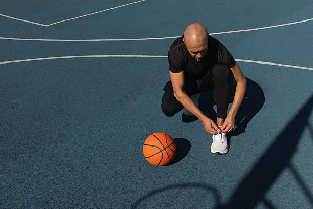 istock Basketball player tying running shoes shoelace before training. 2206372411