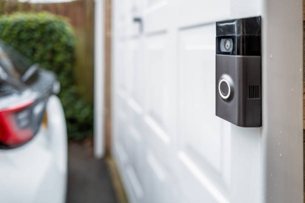 Shallow focus of a popular, battery powered wireless doorbell and integral camera seen located on a driveway, near a side gate entrance. stock photo