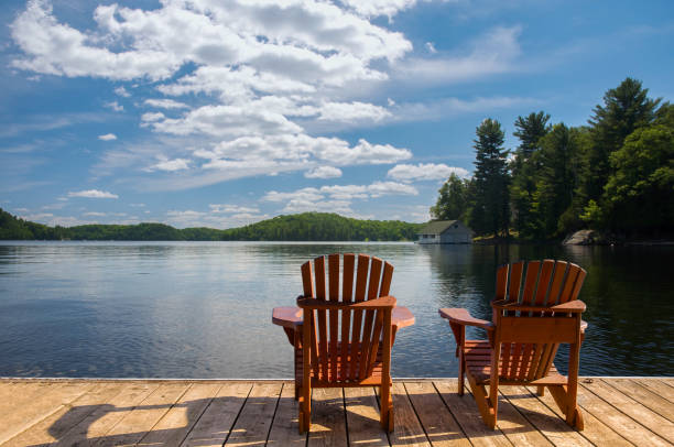 istock Muskoka lake view with chairs on dock, boathouse, trees, copy space. 2206376317
