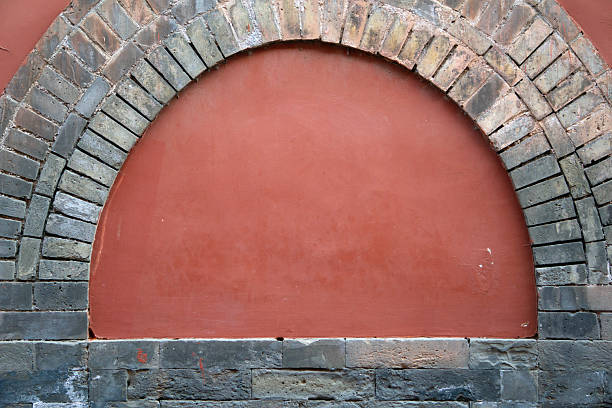 A captivating terracotta red wall with a gracefully arched top and a solid brick base creates a harmonious blend of color and texture.
