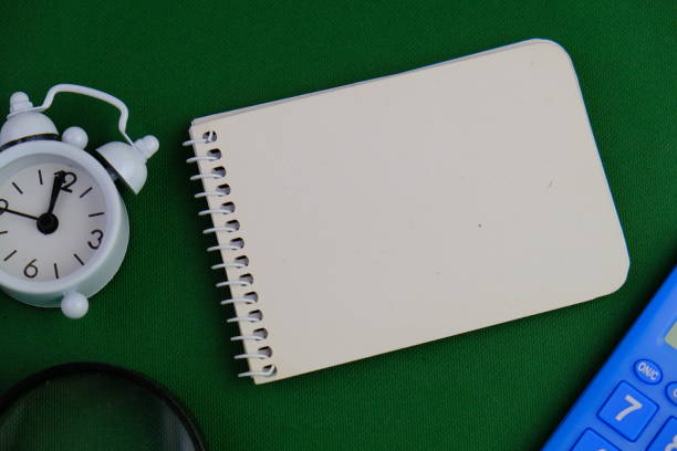 flat lay of a blank note book for text space. Educational and financial concept with text space on green background. surrounded by office tools.