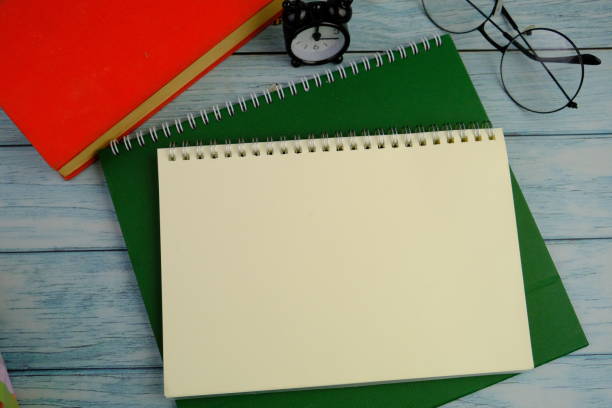 istock flat lay of a blank note book for text space. Educational and financial concept with text space on green background. surrounded by office tools. 2206389280