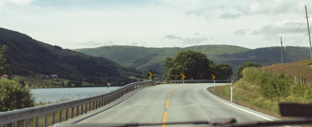car windshield while driving on a Norwegian mountain highway at a bend marked with orange signs