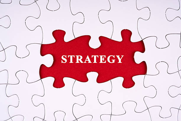 istock Strategy written on red background through a non completed white blank puzzle 2206391708